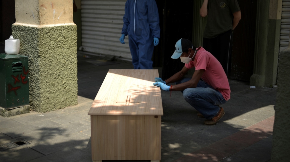 A family member with a coffin holding the body of a man who had died at home in Guayaquil, Ecuador [Vicente Gaibor del Pino/Reuters]