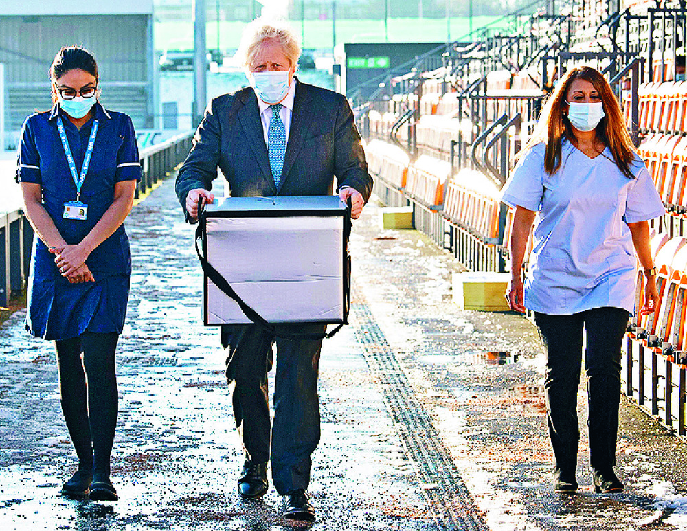 Boris Johnson helps to load doses of vaccine for mobile distribution. Reuters